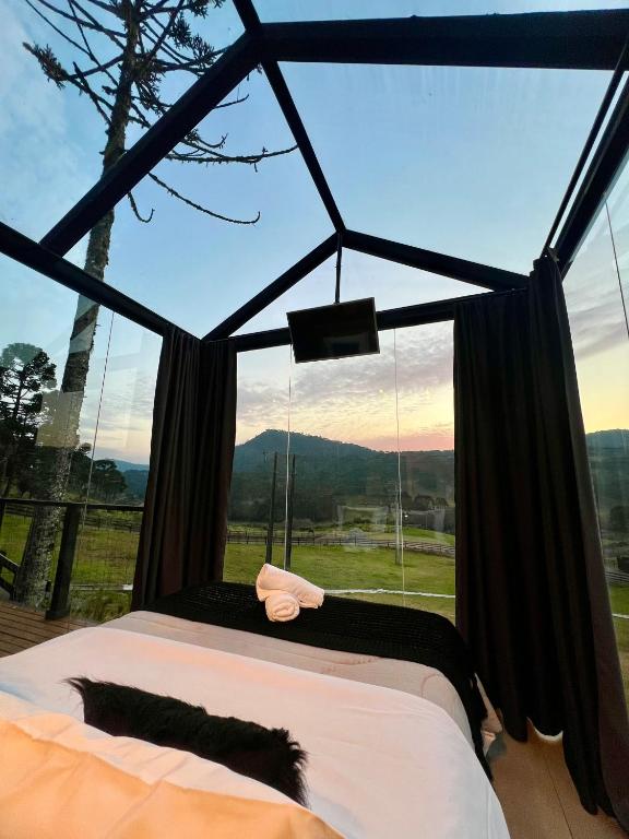 a bedroom with a bed and a large window at Flor da serra in Urubici