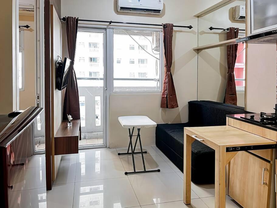 雅加达2BR Apt Green Pramuka with Pool & Wi-Fi by 2ndHome的一间配有沙发、桌子和窗户的客房
