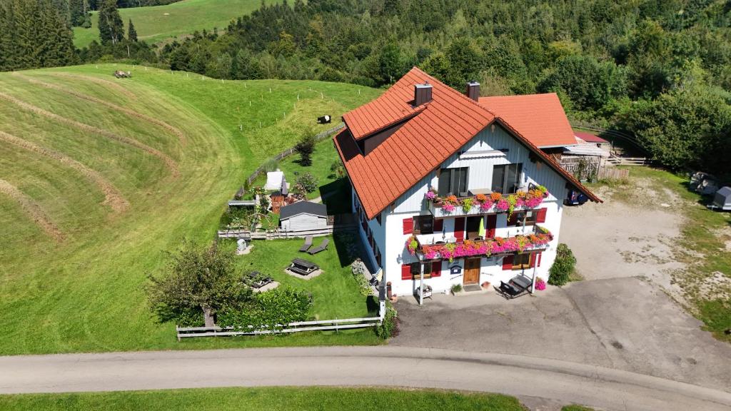 a house with a red roof and flowers in a yard at Altensberger Hof in Gestratz