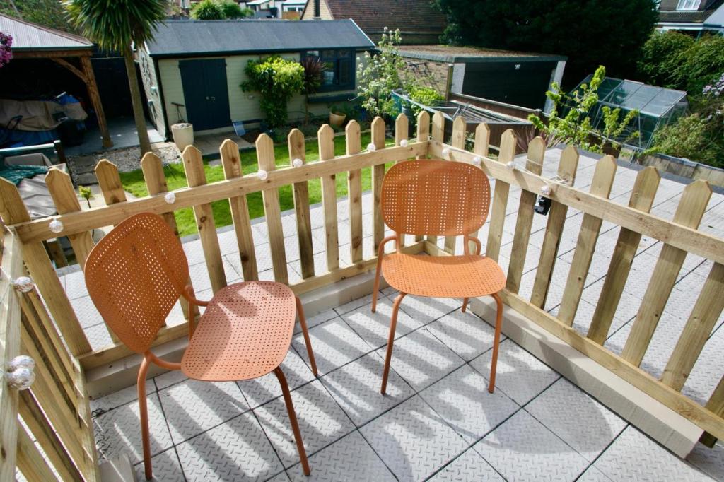 two chairs sitting on a patio next to a fence at Priory park view in Southend-on-Sea