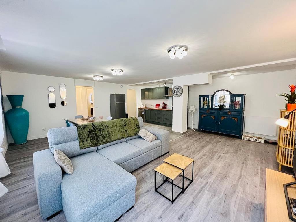 a living room with a blue couch and a kitchen at Le Nid du Sanctuaire in Lourdes