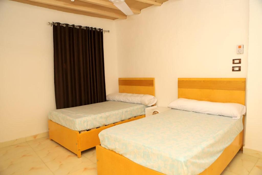 Un dormitorio con dos camas y una ventana. en Karma house, en Luxor