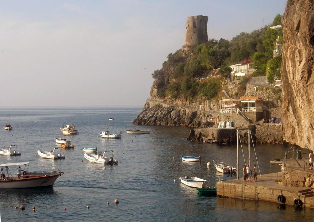 a group of boats in the water near a mountain at Hotel La Conchiglia in Praiano