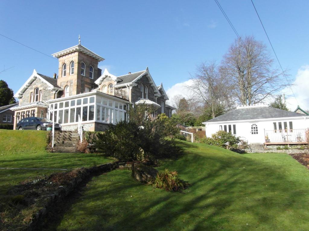 een groot huis op een heuvel met een tuin bij Holly Lodge in Strathpeffer