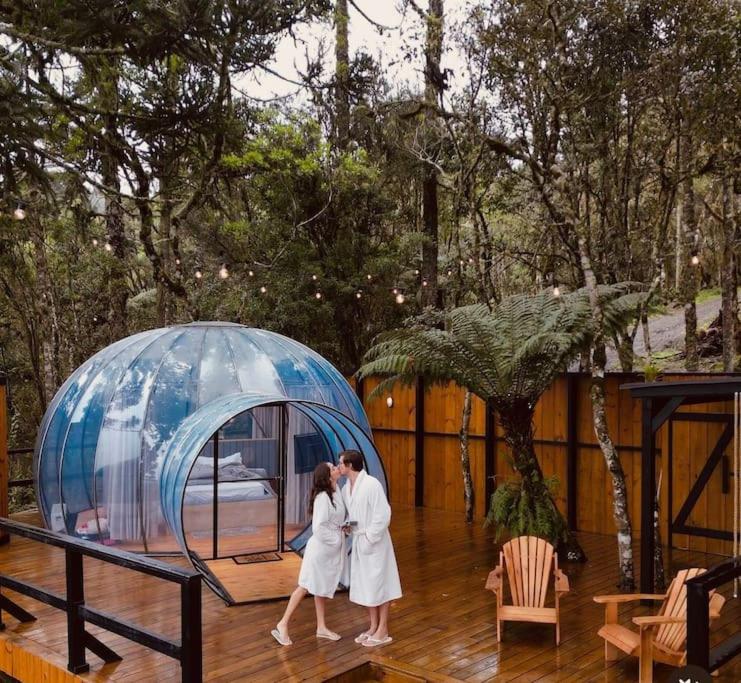 a bride and groom walking in front of a glass dome at Cabana Bolha Urubici in Urubici