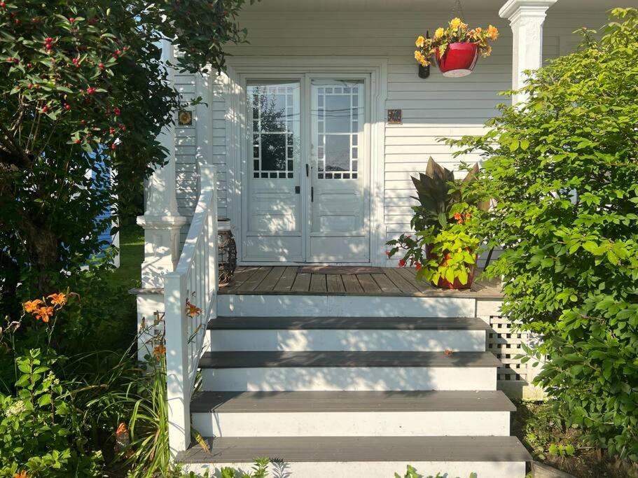 una casa blanca con escaleras que conducen a una puerta en Falls Farmstead 1865 Ellis House Cozy and Comfy Apt #1, en Ellsworth