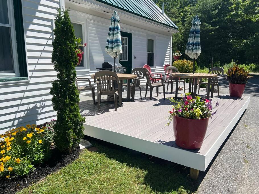 a wooden deck with tables and chairs on a house at Discover Downeast Maine - Comfortable Home Base 37 in Ellsworth