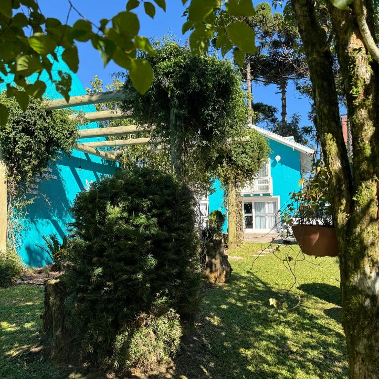 a blue house with a tree in front of it at Pousada Lanai Gramado in Gramado