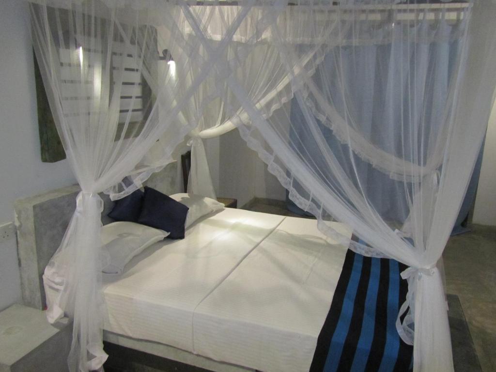 a bedroom with a bed with white curtains at Silva Rest in Unawatuna
