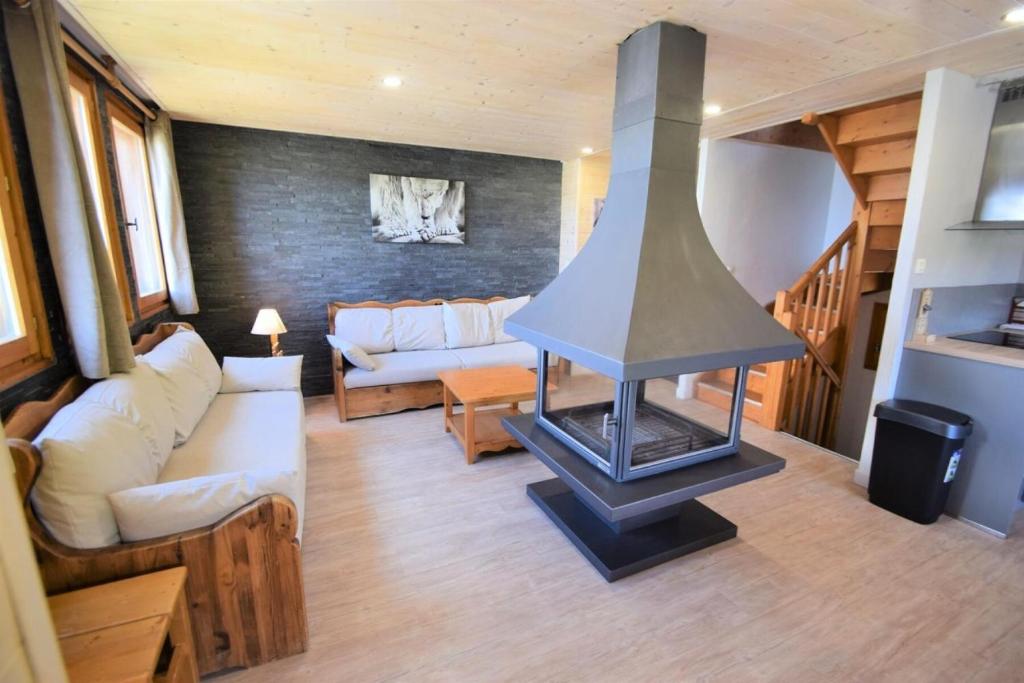 - un salon avec une cheminée au milieu dans l'établissement Les Chalets Des Praz - Chalet LES PRAZ -10 pers - PLAGNE VILLAGES MAE-9674, à Aime La Plagne