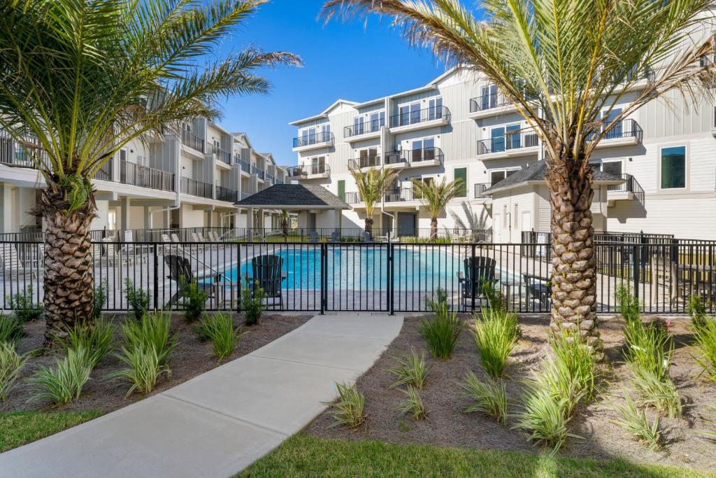 a fence with palm trees in front of a building at One More Time Again by Pristine Properties Vacation Rentals in Mexico Beach