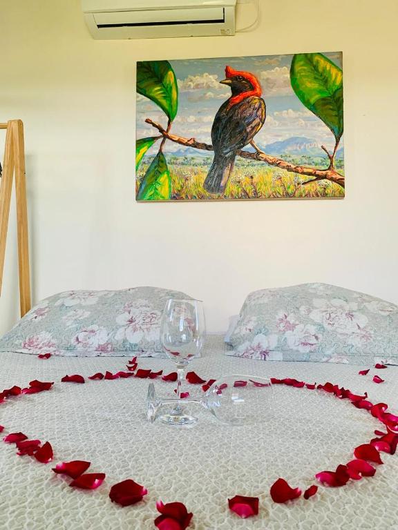 a table with a wine glass and red roses on it at Chales Estrela Veadeiros in Alto Paraíso de Goiás