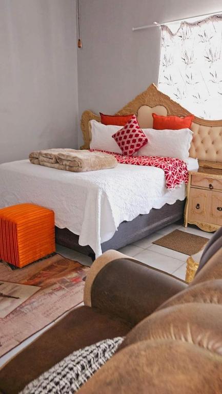 a bedroom with two beds with pillows and a couch at Goodlife guest house in klerksdorp in Klerksdorp