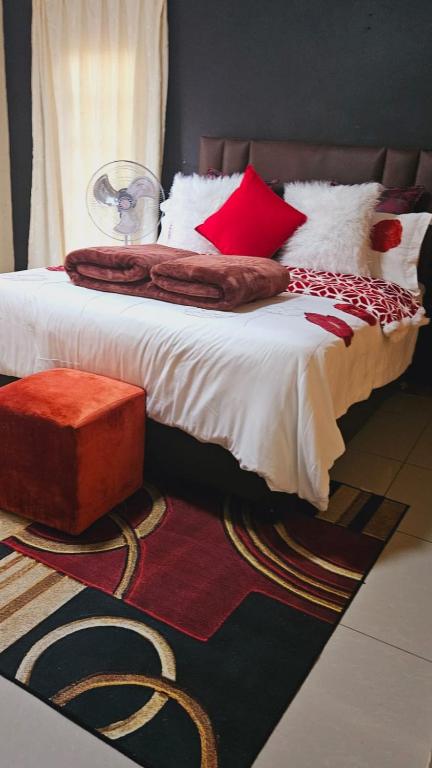 a bedroom with a large bed with red pillows at Goodlife guest house in klerksdorp in Klerksdorp