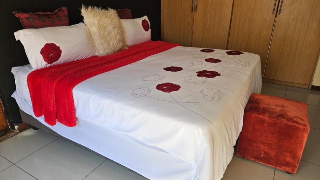 a bed with a red and white blanket on it at Goodlife guest house in klerksdorp in Klerksdorp