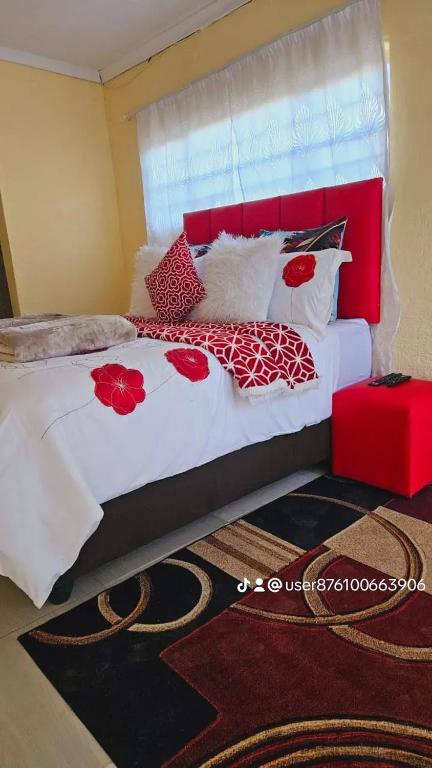 a bedroom with a large bed with red and white pillows at Goodlife guest house in klerksdorp in Klerksdorp
