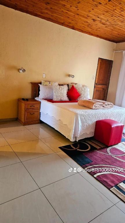 a bedroom with a bed with white sheets and red pillows at Goodlife guest house in klerksdorp in Klerksdorp
