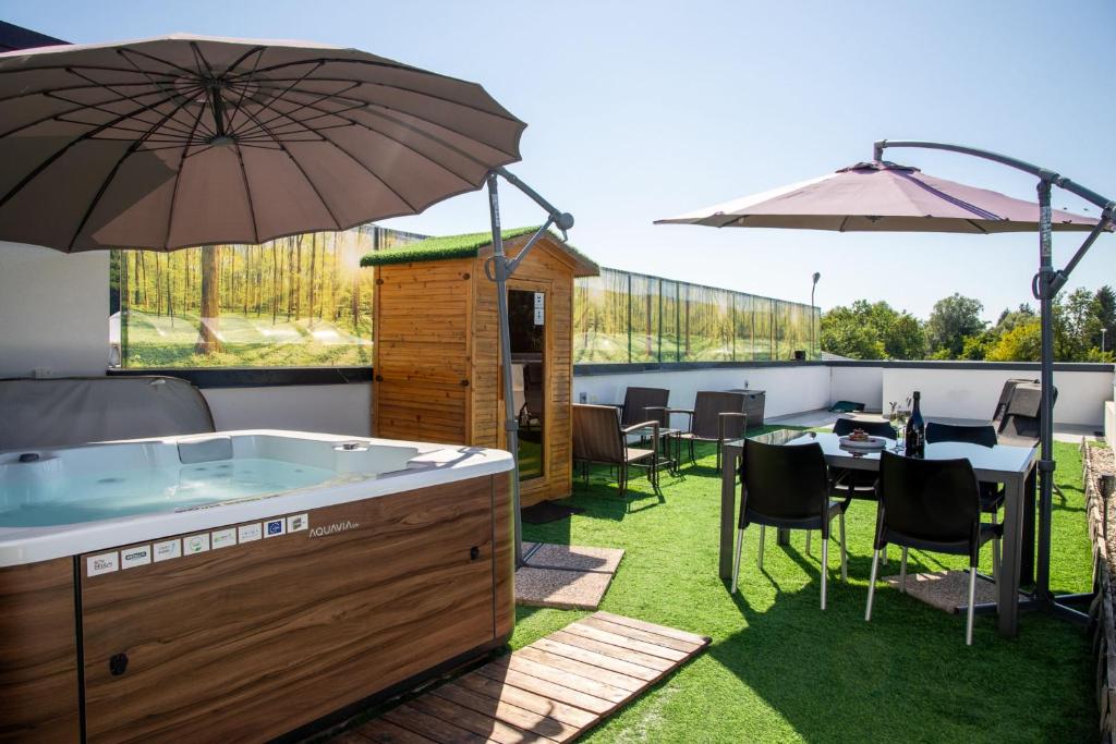 a hot tub on a patio with an umbrella at Rooftop Home With Whirlpool & Sauna - Happy Rentals in Trebnje