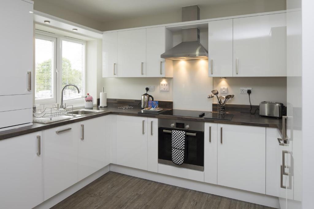 a white kitchen with white cabinets and a sink at House of Fisher - Beneficial House in Bracknell