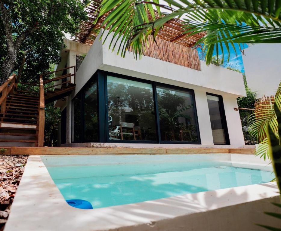 a villa with a swimming pool in front of a house at The Village K´AAX in Tulum