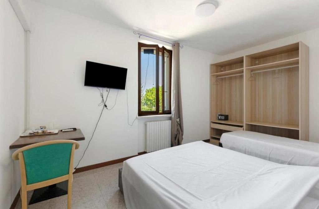 una camera con 2 letti, una scrivania e una TV di La Terrazza Guest House a San Zeno