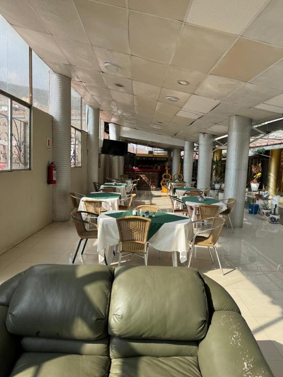 una sala da pranzo con tavoli, sedie e un divano di Hotel Plateros a Cuzco
