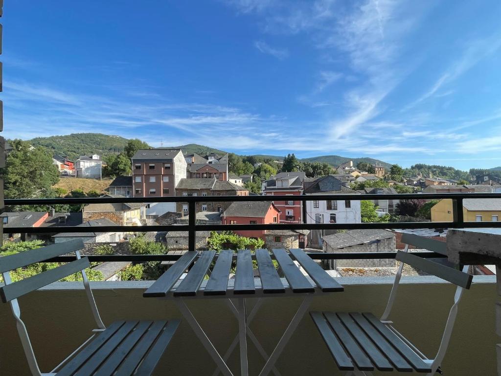 a bench on a balcony with a view of a city at Los Balcones de Vega in Vega de Espinareda