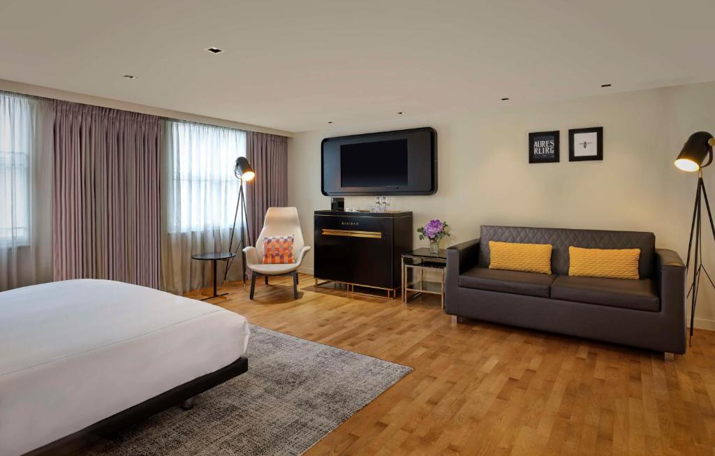 a bedroom with a bed and a couch and a tv at Holmes Hotel London in London