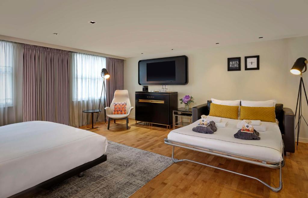 a hotel room with a bed and a flat screen tv at Holmes Hotel London in London