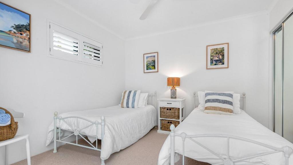 a white room with two beds and a chair at Unit 3 21 Park Generous and Comfortable Beachside Abode in Sunshine Beach