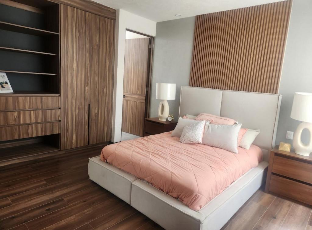 a bedroom with a bed with pink sheets and wooden floors at Habitación Doble in Morelia