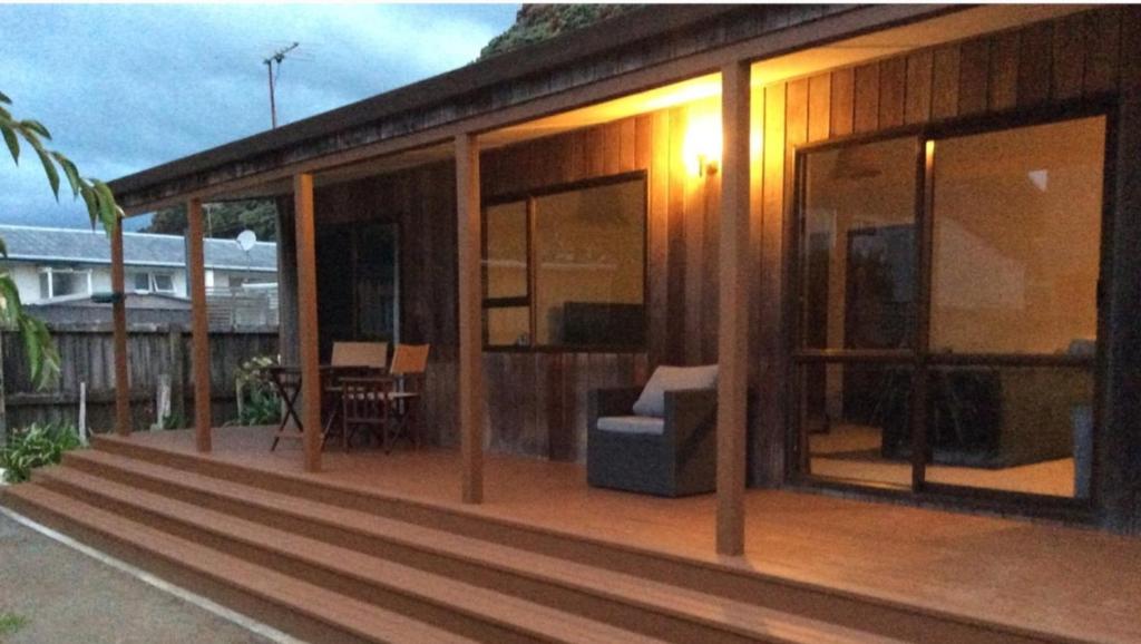 a house with glass doors and a couch on a deck at Pohutukawa Cottage in Ohope Beach