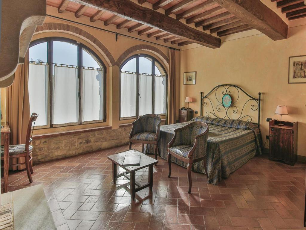 een slaapkamer met een bed, stoelen en ramen bij Hotel Le Pozze Di Lecchi in Gaiole in Chianti
