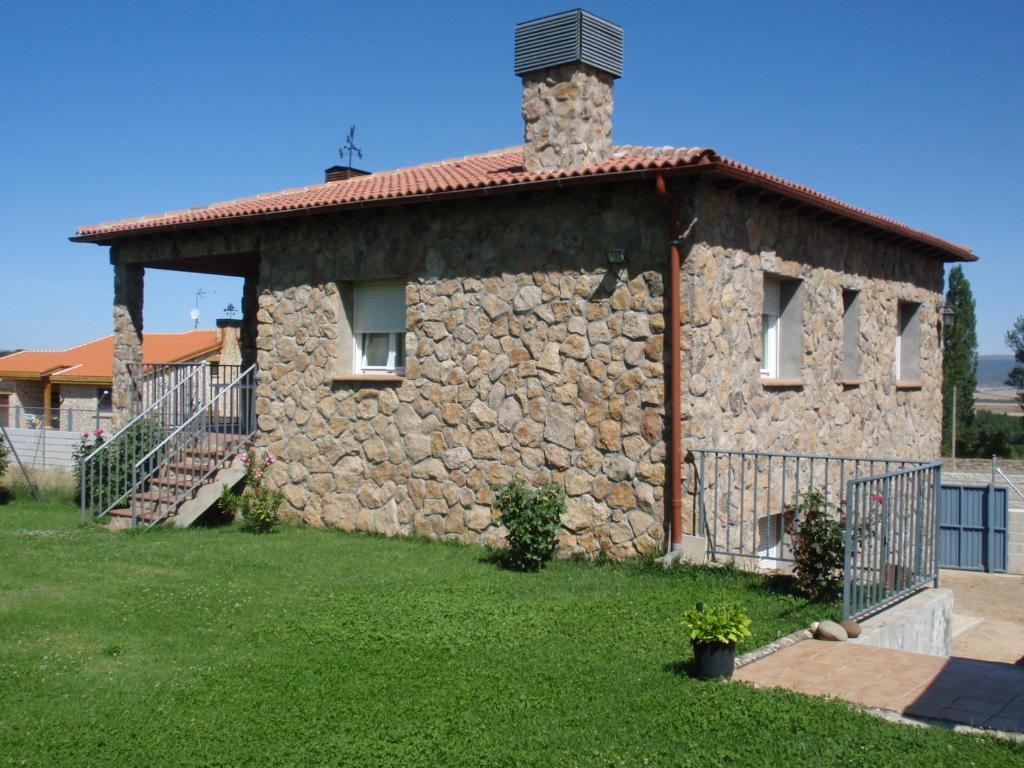 una casa de piedra con una chimenea encima en Casa Rural El Castillo, en Palacio