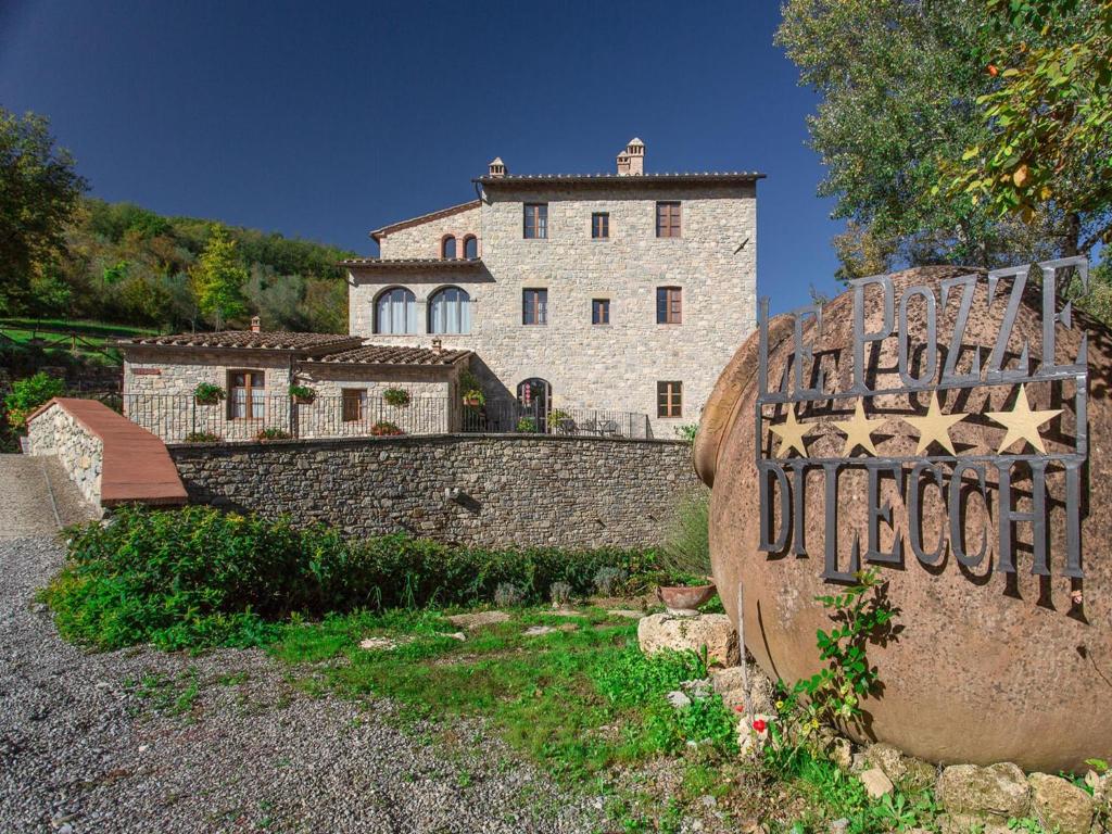 a large stone building with a clock on the side of it at Hotel Le Pozze Di Lecchi in Gaiole in Chianti