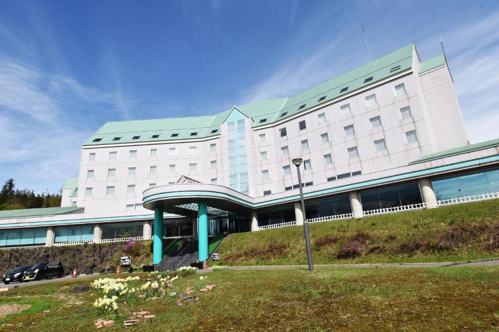 美瑛町にあるBiei Shirogane Onsen Hotel Park Hillsの緑の屋根の白い大きな建物