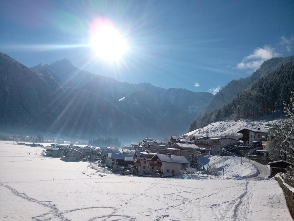 Ein Dorf im Schnee mit der Sonne am Himmel in der Unterkunft Ferienwohnung Zuppinger in Mayrhofen