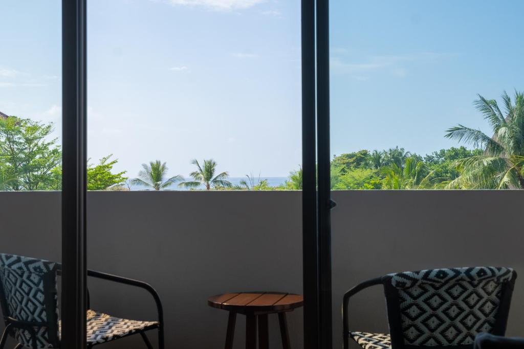 a room with two chairs and a table and a window at MERUSAKA Nusa Dua in Nusa Dua