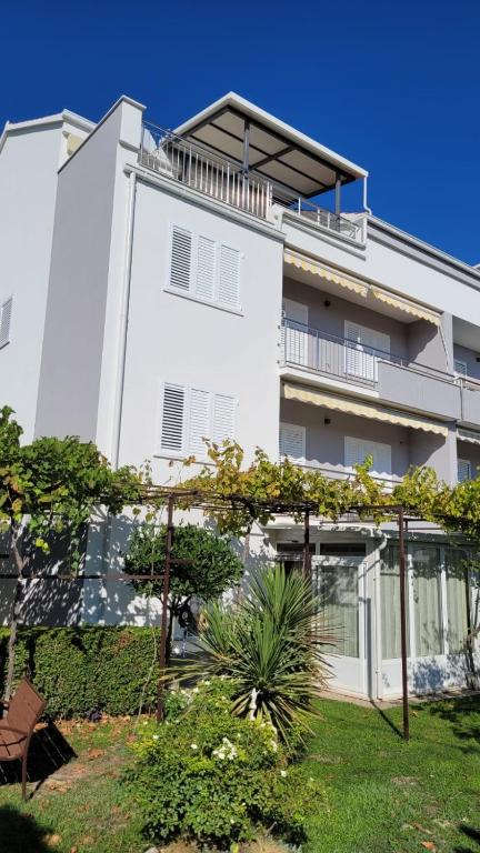 a white apartment building with a garden in front of it at Sunshine Apartments Podstrana in Podstrana