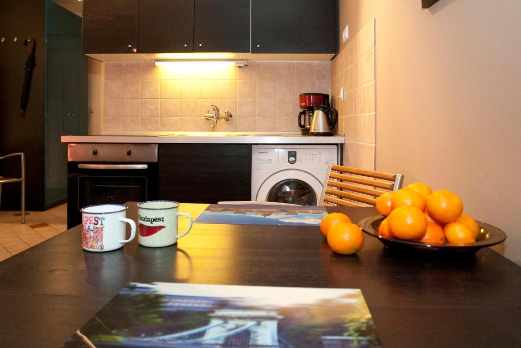 una cocina con una mesa con un tazón de naranjas. en Gloria Apartment en Budapest