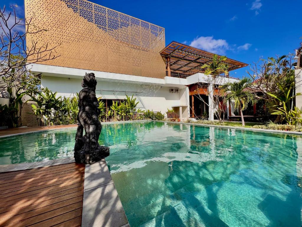 a swimming pool with a statue in front of a building at D'Avera Villa Canggu in Canggu