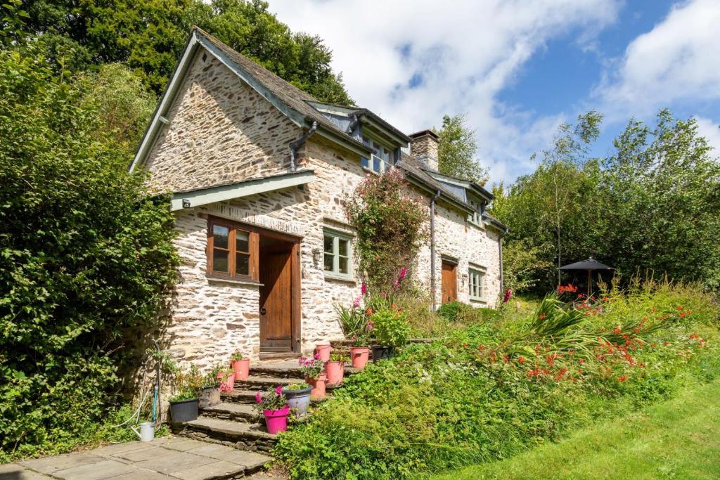 Butterfly Cottage في Wheddon Cross: أمامه بيت حجري فيه خزاف