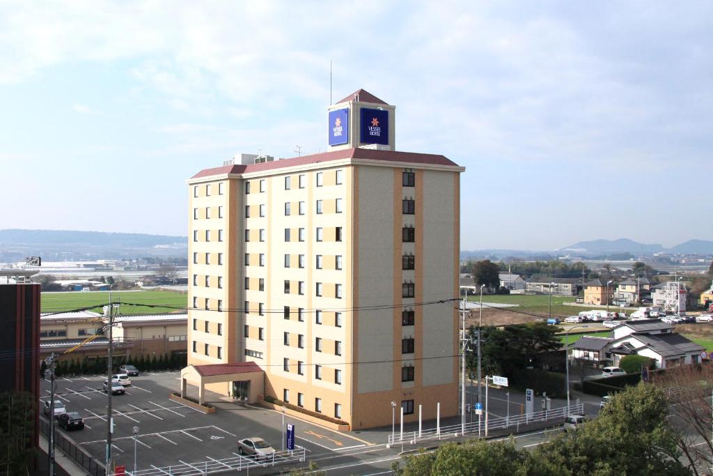 um edifício alto com uma torre de relógio em cima em Vessel Hotel Kumamoto Airport em Ozu