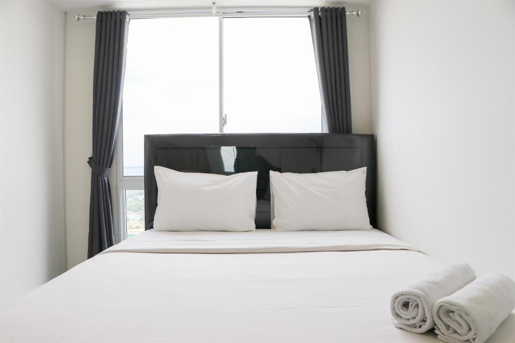 RawalembangComfort and Minimalist 2BR Apartment Tokyo Riverside PIK 2 By Travelio的一张带白色床单和枕头的床,位于窗户前