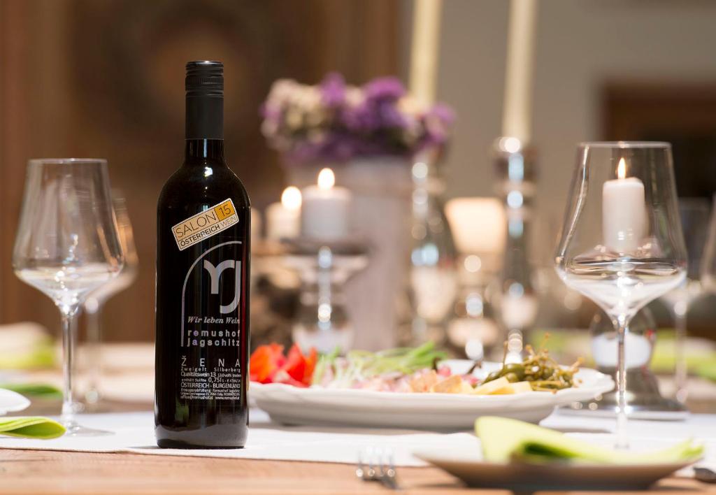 a bottle of wine sitting on a table with wine glasses at Remushof Jagschitz in Oslip