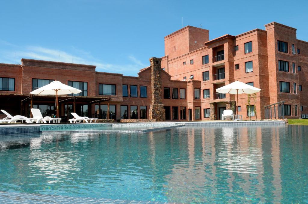 a swimming pool with chairs and umbrellas in front of a building at Regency Park Hotel in Montevideo