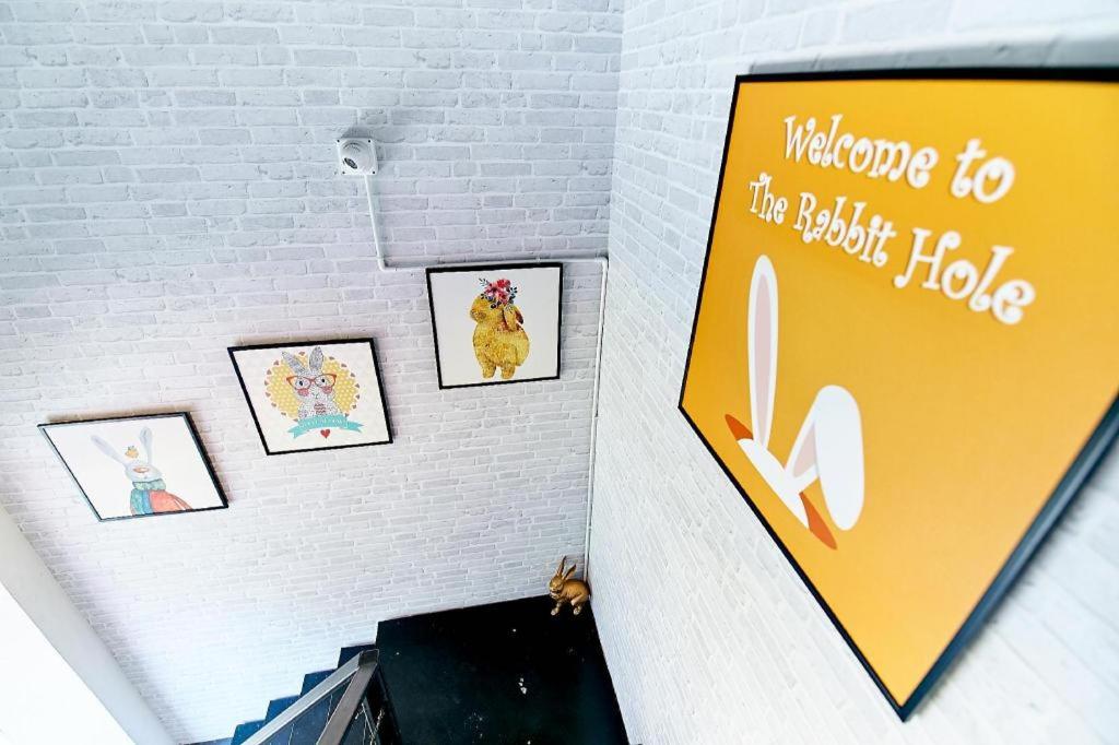 a yellow sign on a wall with pictures on it at The rabbit's hole hostel in Bangkok