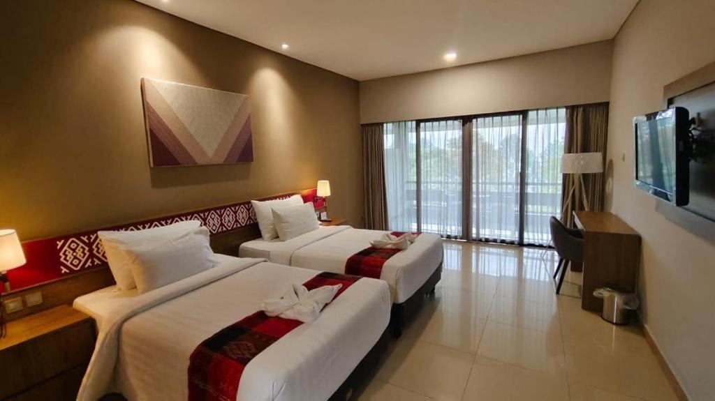 a hotel room with two beds and a television at Patra Comfort Parapat in Parapat