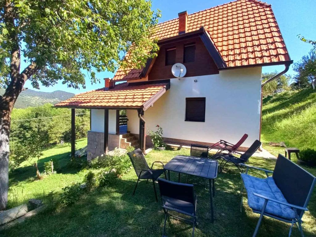 a house with chairs and a table in the yard at House Tara Zaovine Sleeps 10 in Zaovine