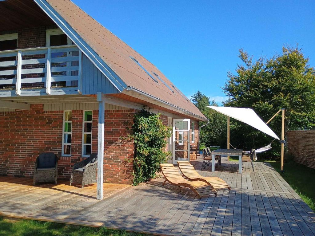 a house with a deck with chairs and a table at Family-Friendly Home Near Beach, Forest, Harbour in Ålbæk